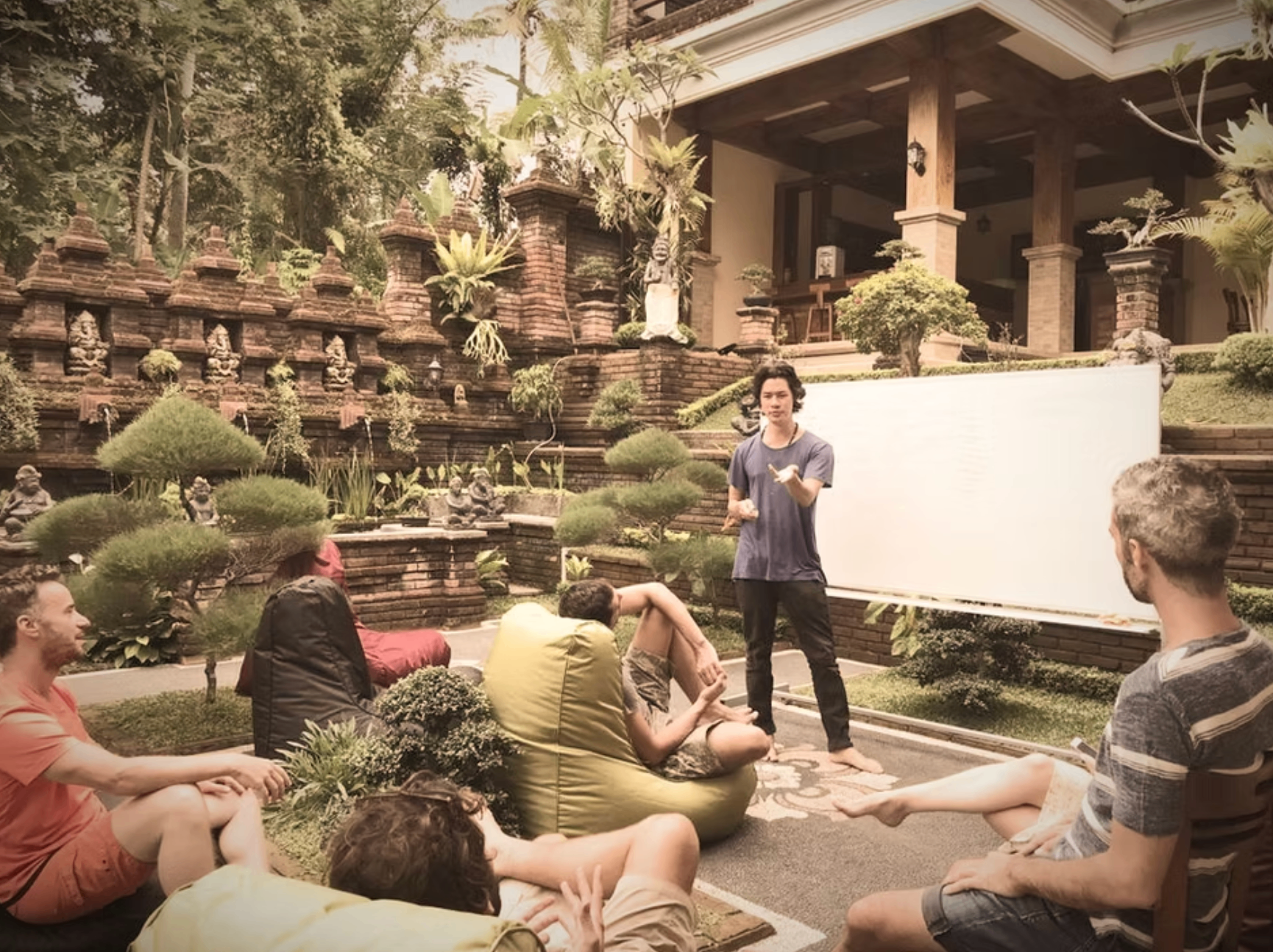 An intimate outdoor discussion with engineers gathered around a presenter in a Balinese courtyard