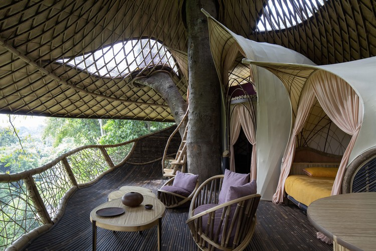 Curved bamboo loft interior with a four-poster bed and valley view
